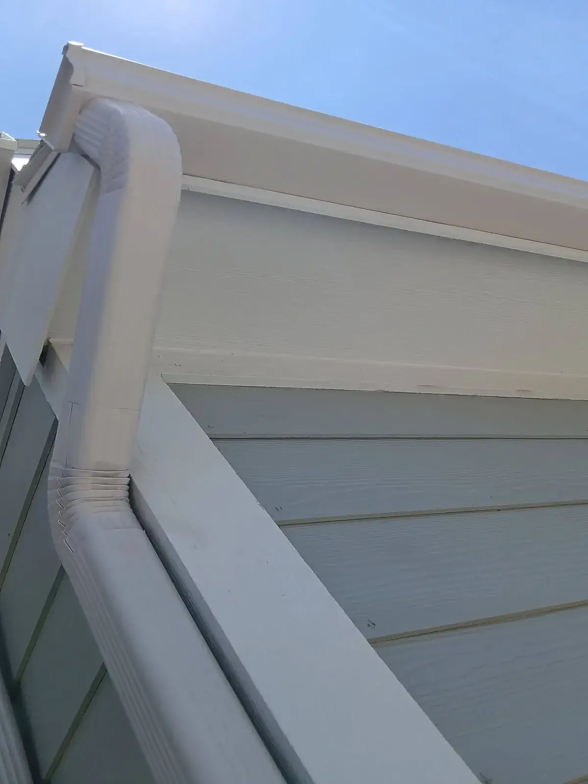 White gutter installation along a roof edge